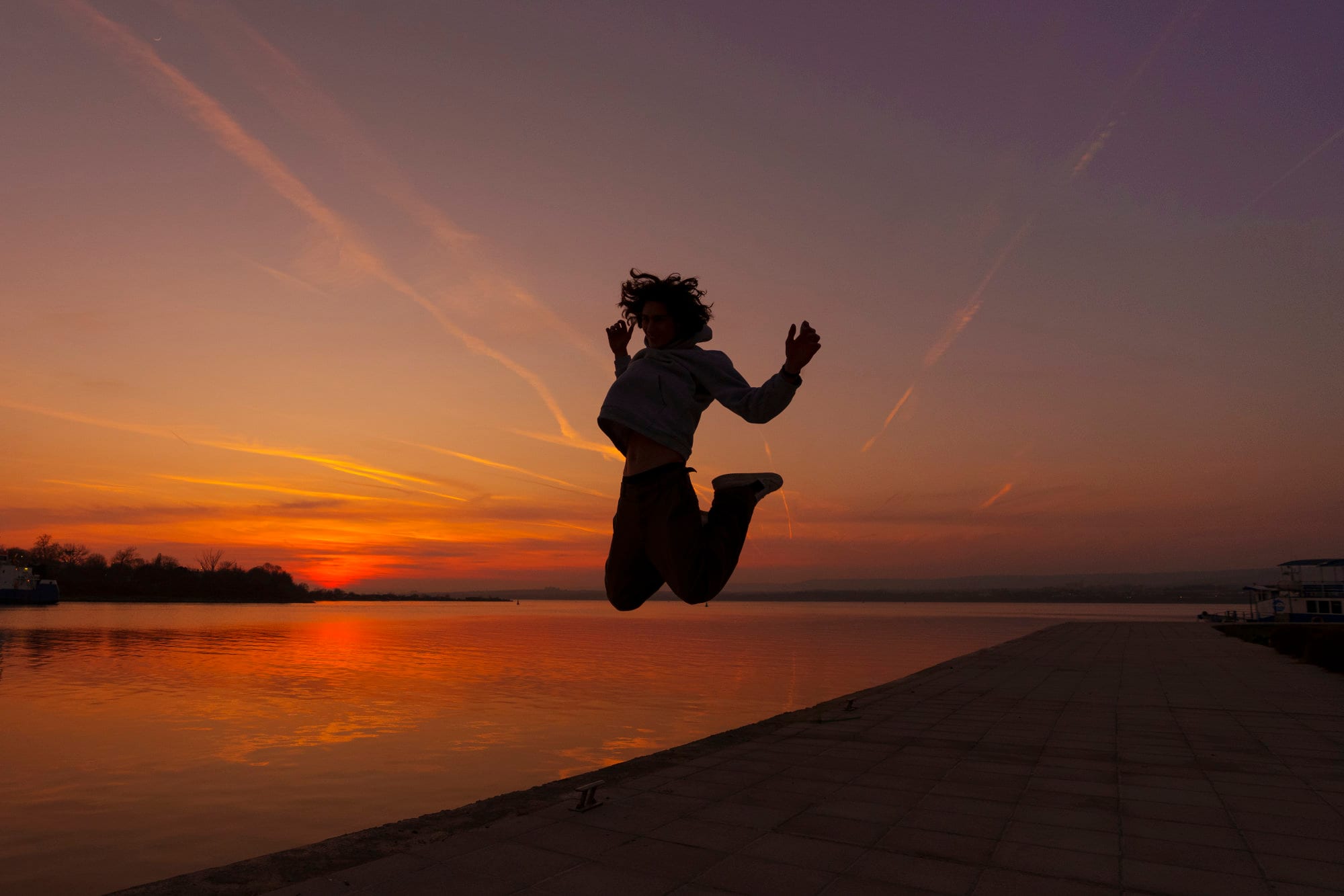 A woman leaping joyfully on a beach at sunset